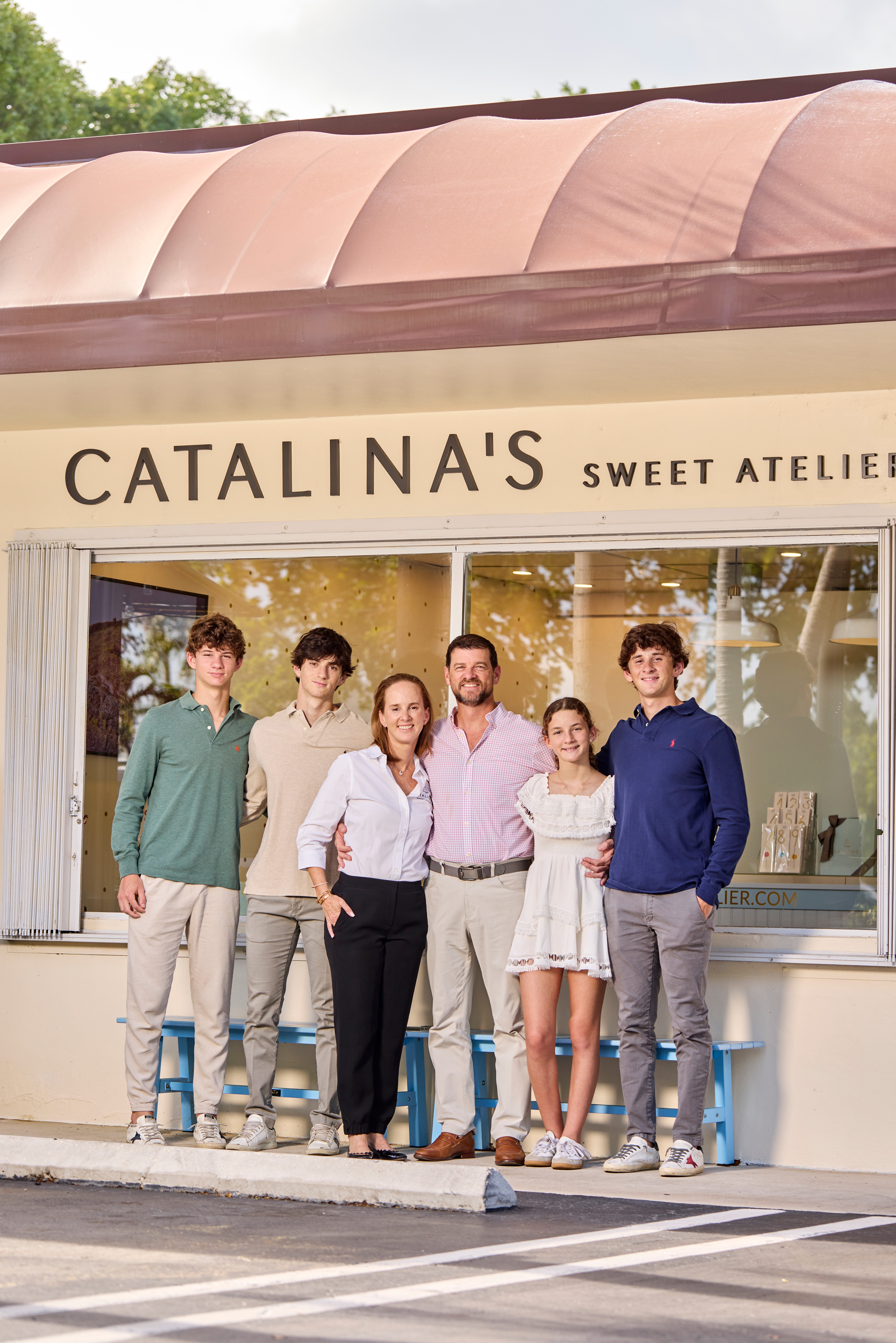 Group of six people standing outside a bakery named Catalina's Sweet Atelier, smiling, with a storefront window behind them.